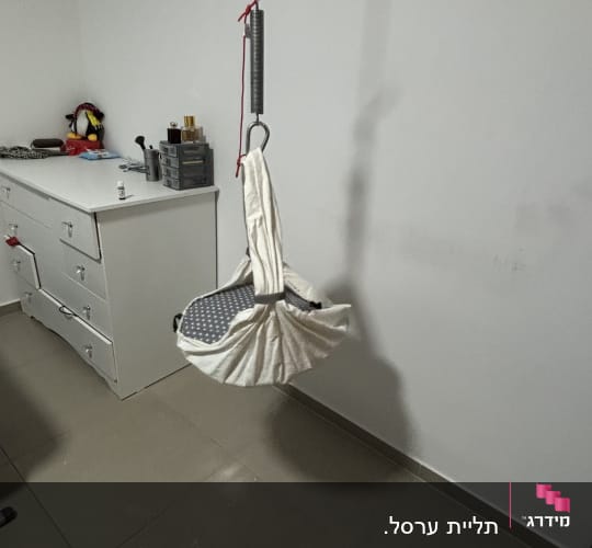 חדר עם מתקן תלוי מהתקרה ליד שידה